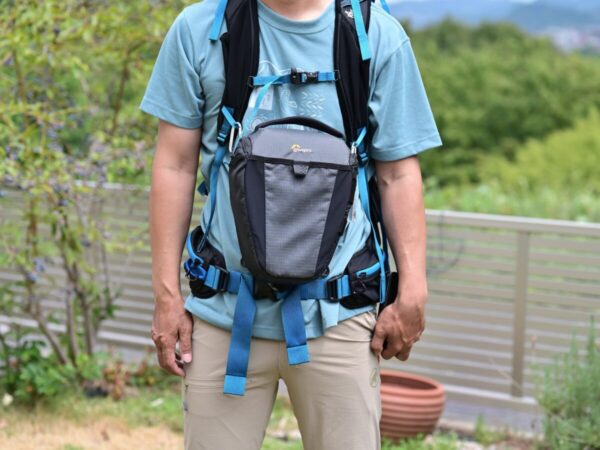 ショルダーハーネスのベルトにカメラバッグを取り付けた人の画像